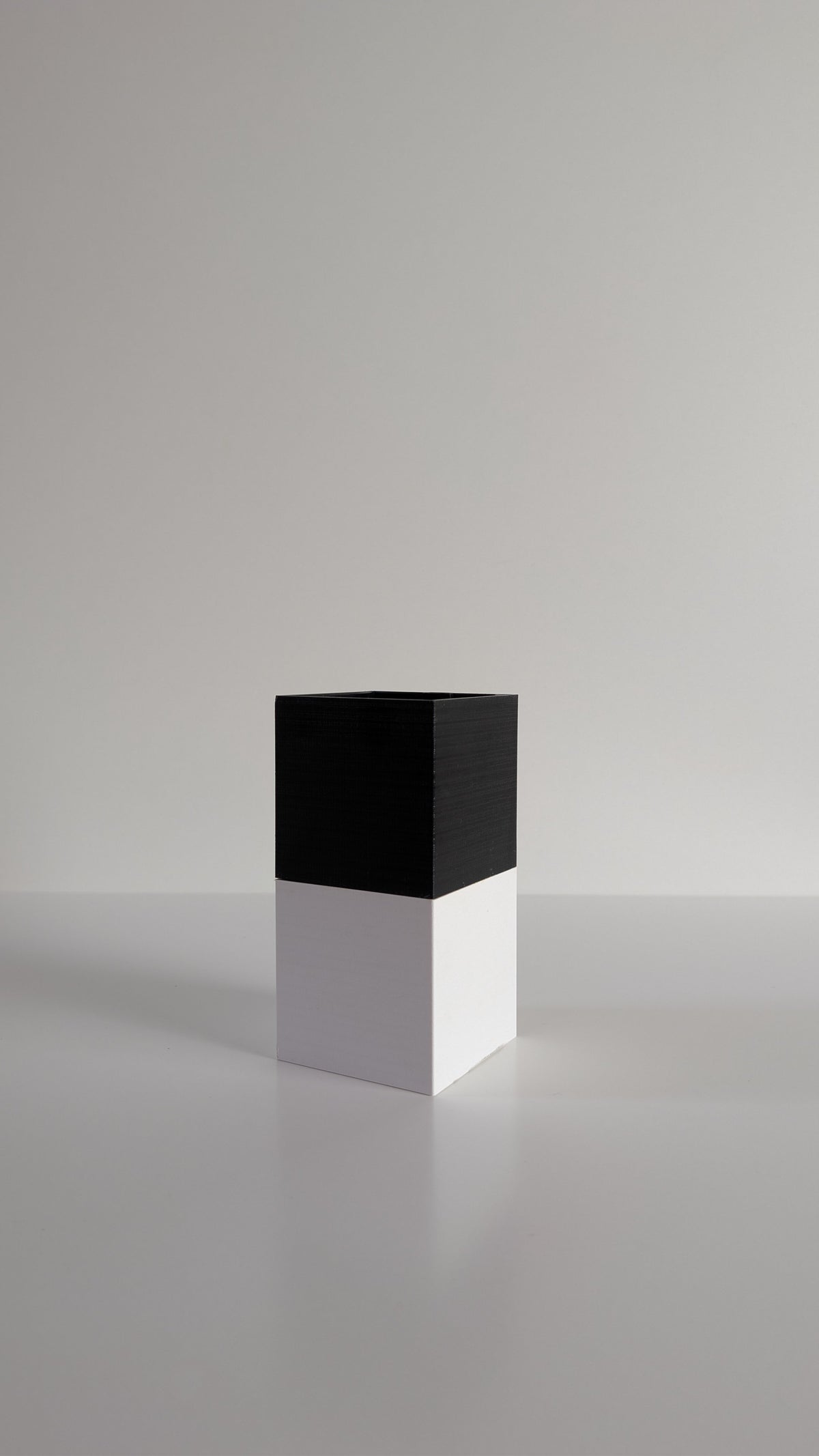 Cache-pot à arrosage autonome Le Cube Éclance bicolore, module haut noir et module bas blanc, sans plante, sur fond neutre
