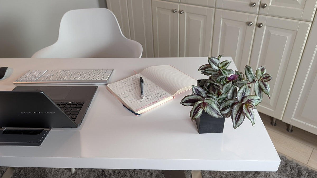 Cache-pot Le Cube Éclance noir : un cache-pot noir posé sur un bureau blanc à côté d'un carnet de notes.