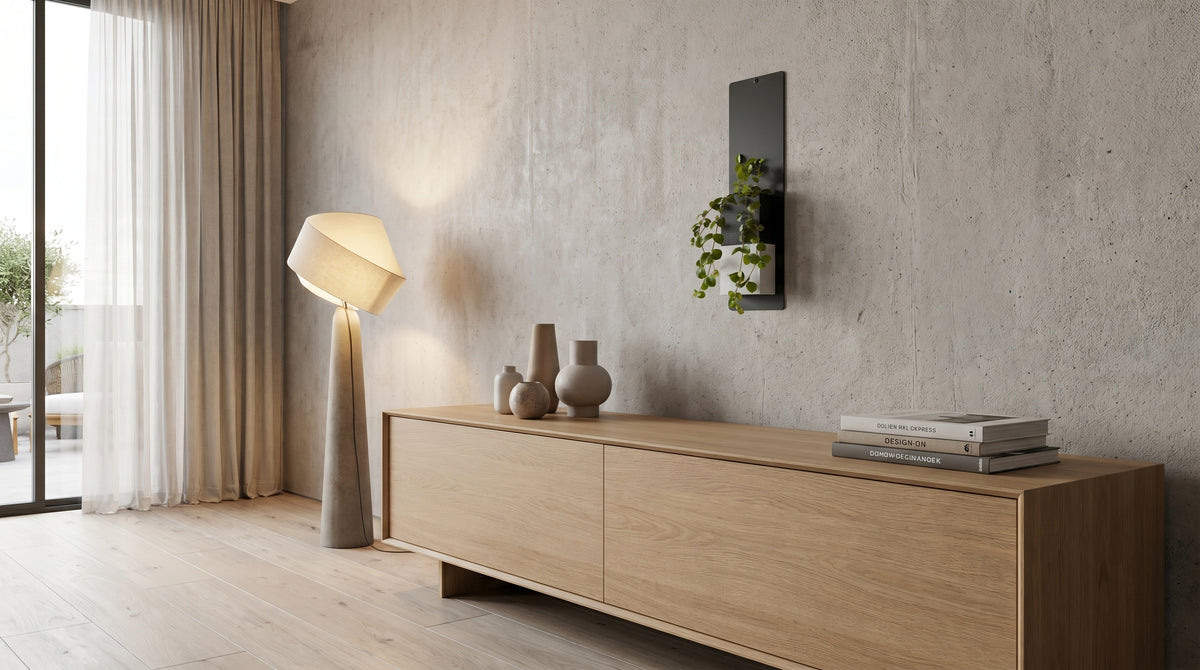 Aménagement d'un salon au design minimaliste avec un mur aspect béton et un grand buffet en bois clair. Au-dessus du meuble, une belle plante verte tombante est mise en valeur dans le cache-pot Le cube bicolore noir et blanc de la marque Éclance décoration intérieur végétal. Ce cache-pot, spécialement adapté pour un pot de 6cm, est fixé sur un support mural vertical noir.