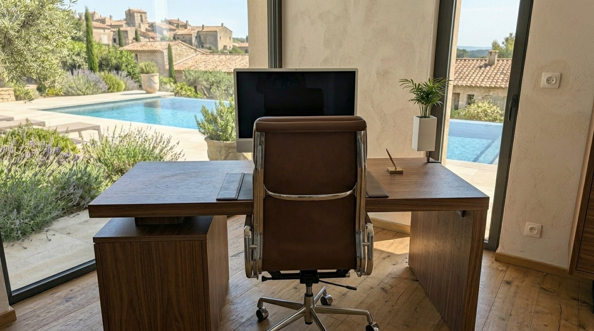 Un bureau de luxe avec un fauteuil de direction en cuir marron. Un îlot végétal Éclance avec un cache-pot Le cube blanc (pour pot de 6cm) est fixé sur le bureau en noyer, contenant un palmier. L'arrière-plan offre une vue imprenable sur une piscine à débordement et un village méditerranéen en pierre.