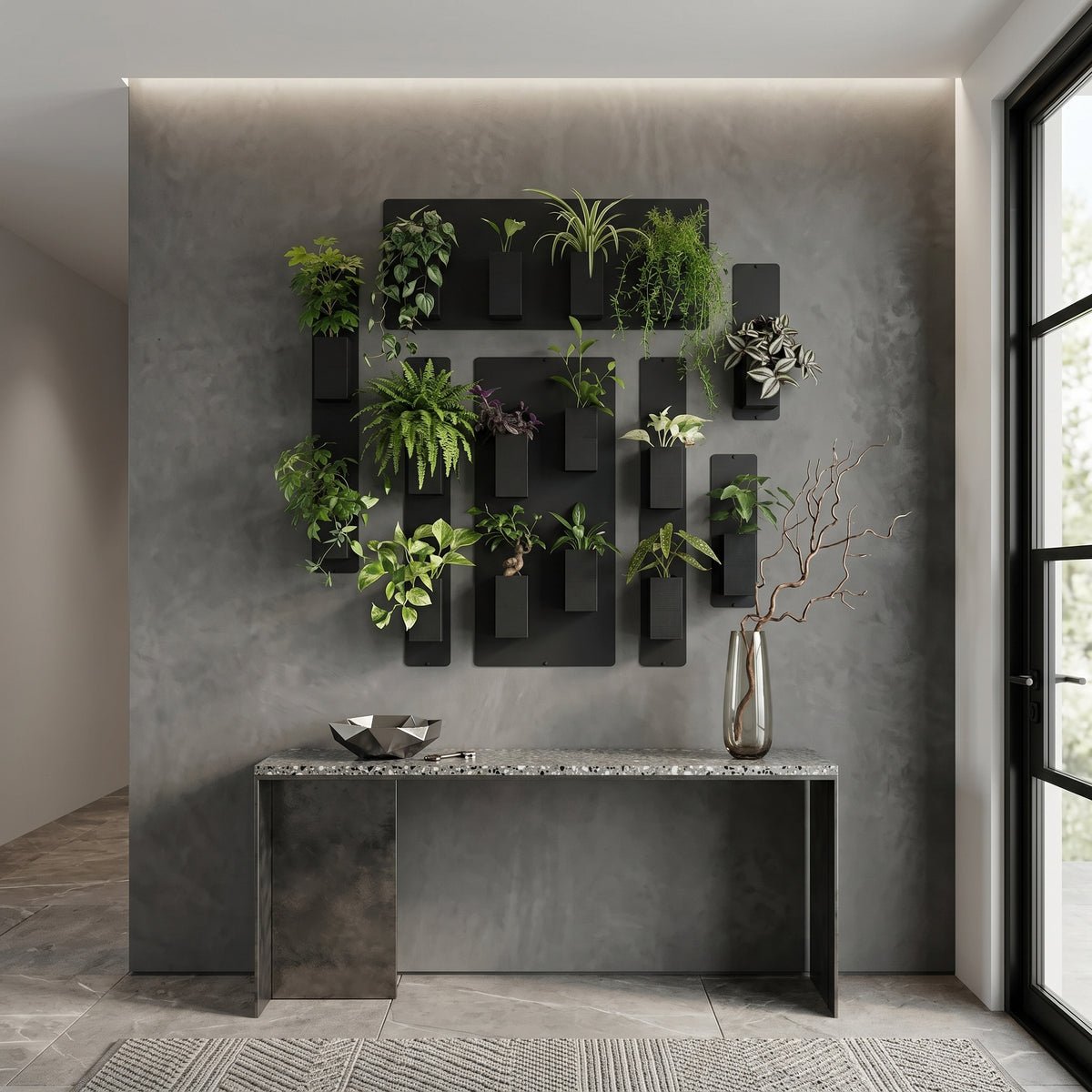 Une élégante composition de mur végétal de la marque Éclance décoration intérieur végétal, disposée sur un grand mur texturé gris à l'effet béton ciré. L'installation modulaire comprend plusieurs supports magnétiques noirs habillés de cache-pots Le cube tout noir, parfaitement adaptés pour un pot de 6cm, contenant une variété de plantes vertes luxuriantes. En dessous, une console moderne au plateau en terrazzo gris accueille un grand vase en verre avec des branches décoratives et une coupelle métallique.