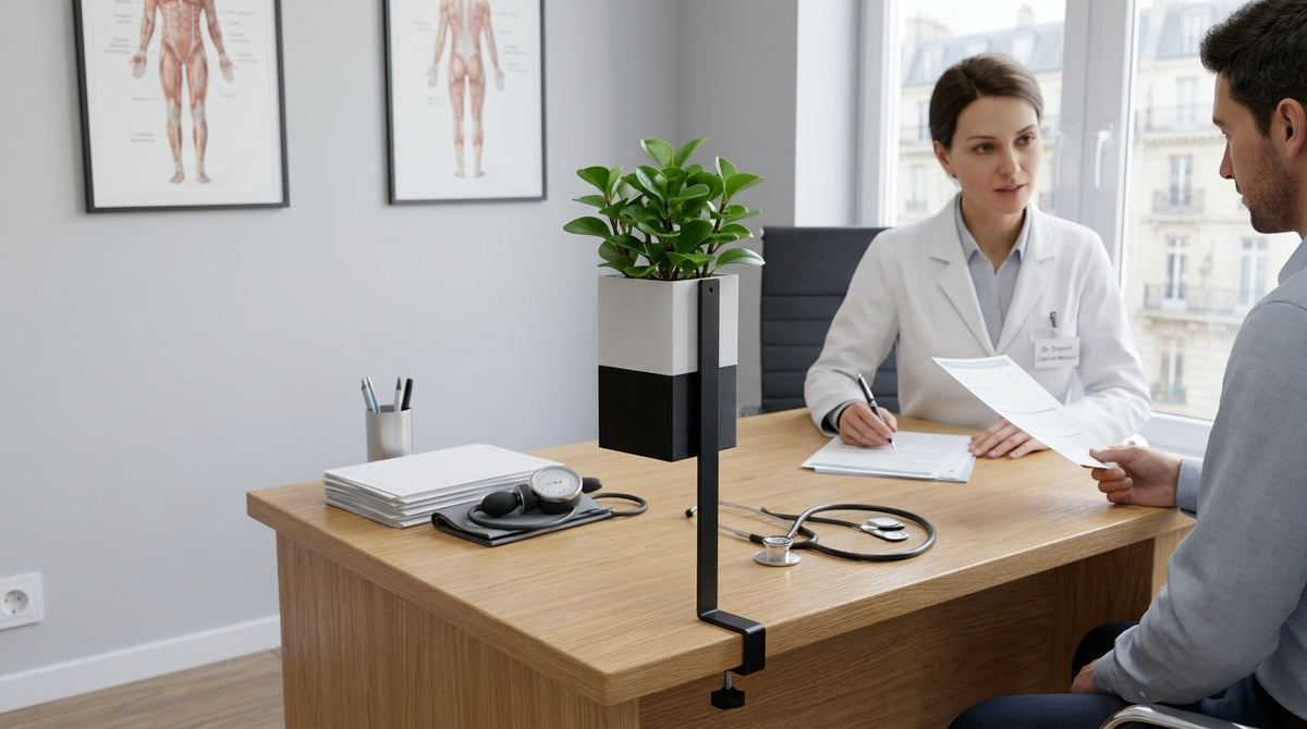 Photo nette montrant le cache-pot cubique Éclance 'Le cube' (bicolore blanc et noir, pour pot de 6cm) fixé au support de bureau 'L'îlot végétal' sur un bureau de médecin. Un médecin et un patient sont en arrière-plan.