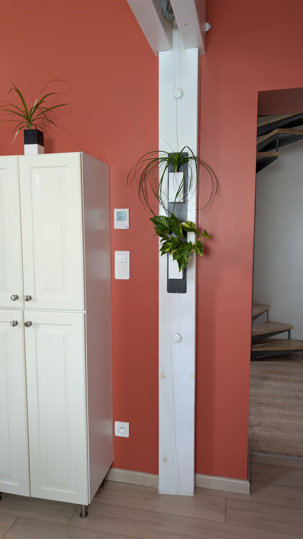 Mini mur végétal Éclance M2 blanc : support mural végétal blanc suspendu à un poteau en bois dans une pièce moderne.