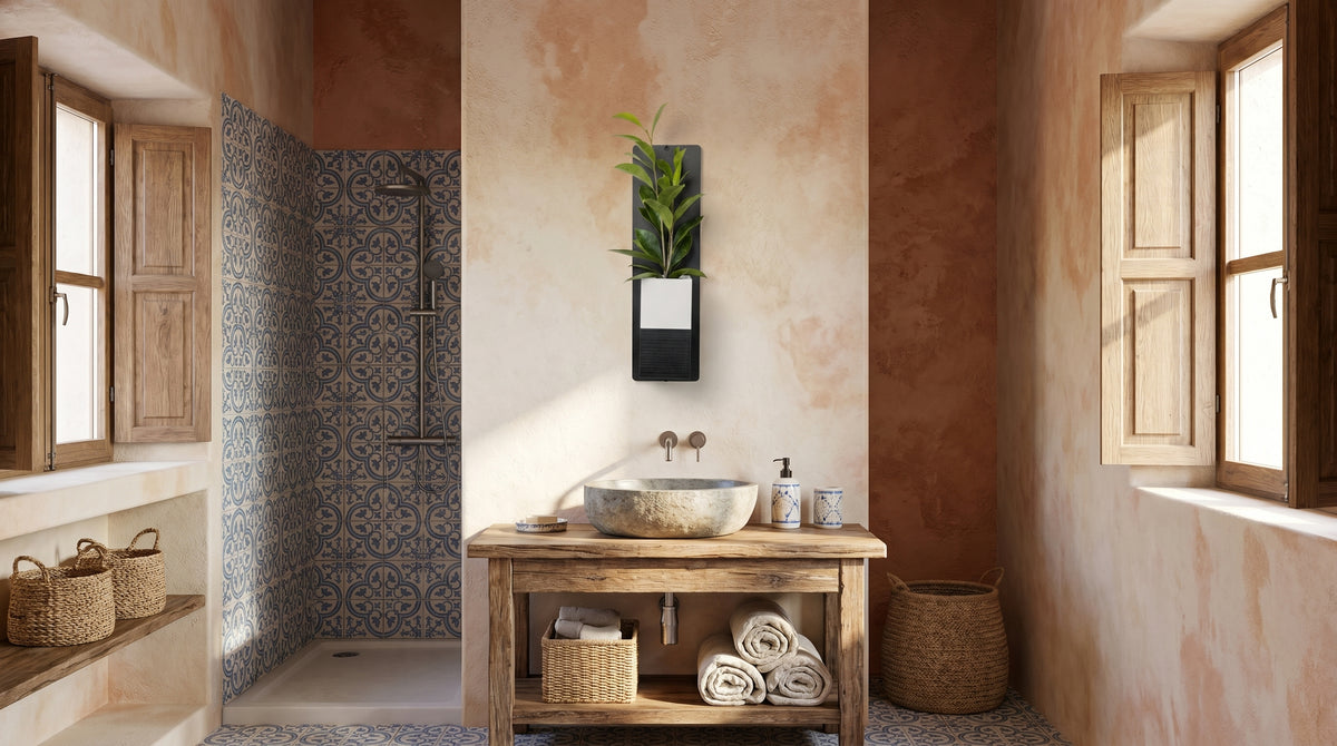 Décoration d'intérieur végétale Éclance dans une salle de bain de style méditerranéen avec douche en azulejos et murs terracotta. Fixé au centre au-dessus d'une vasque en pierre et d'un meuble en bois rustique, le mini mur végétal sur plaque en acier noir accueille un cache-pot Le Cube bicolore blanc et noir, adapté pour un pot de 6cm, d'où s'élance une plante verte.