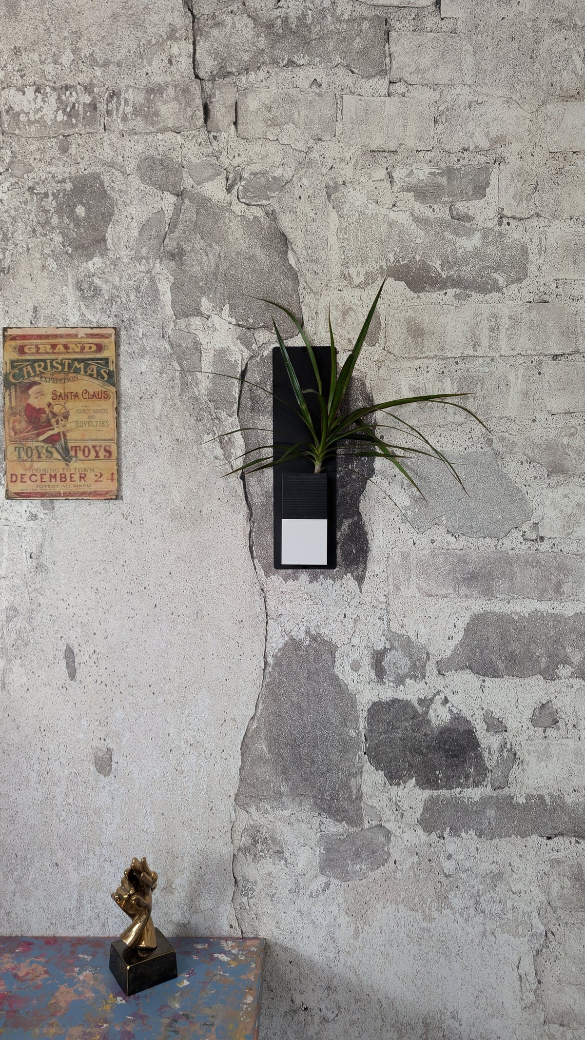 Mini mur végétal Éclance M1 bicolore (cube haut noir, cube bas blanc) : support mural végétal noir et blanc fixé sur un mur en pierre rustique.