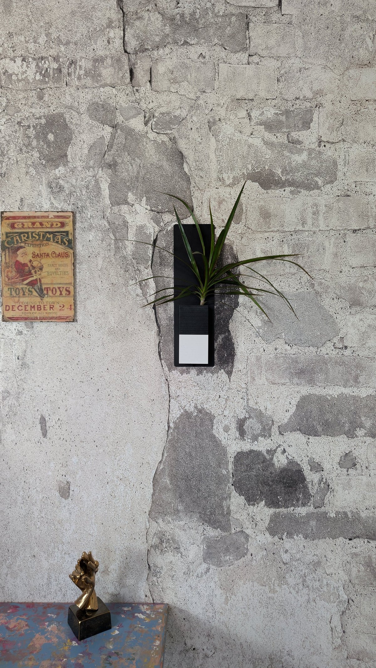 Mini mur végétal Éclance M1 bicolore (cube haut noir, cube bas blanc) : support mural végétal noir et blanc accroché sur un mur en briques anciennes brutes.