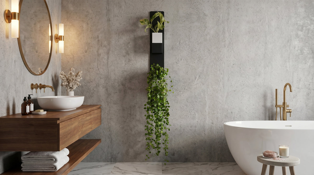Aménagement d'une salle de bain moderne et relaxante avec mur en béton ciré, meuble vasque en bois et baignoire îlot. Au centre de la pièce, un support mural vertical en métal noir de la marque Éclance décoration intérieur végétal accueille une luxuriante composition végétale. Celle-ci est disposée dans deux cache-pots Le Cube, spécialement adaptés pour des pots de 6cm : un modèle bicolore noir et blanc en haut, et un modèle unicolore tout noir en bas d'où cascade une impressionnante plante retombante.